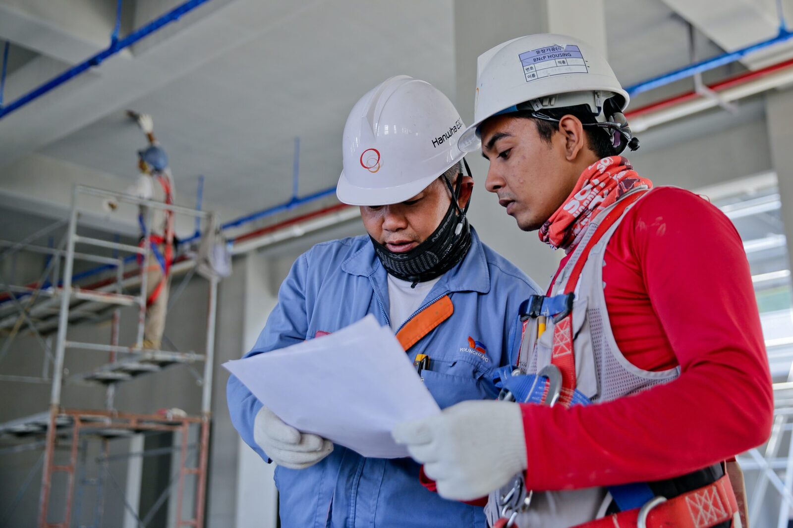 A senior site engineer talking a young worker through a drawing on site
